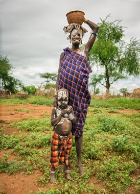 Woman from the african tribe Mursi with her baby, Ethiopia clipart