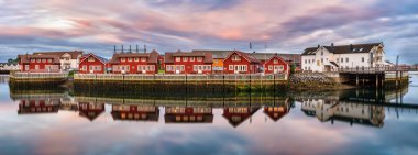 Red harbor houses in Svolvaer, Norway at sunset clipart