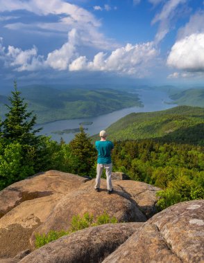 Yürüyüşçü Kara Dağ 'da duruyor, George Gölü ve New York Eyaleti' nin çevresindeki Adirondack manzarasının tadını çıkarıyor..