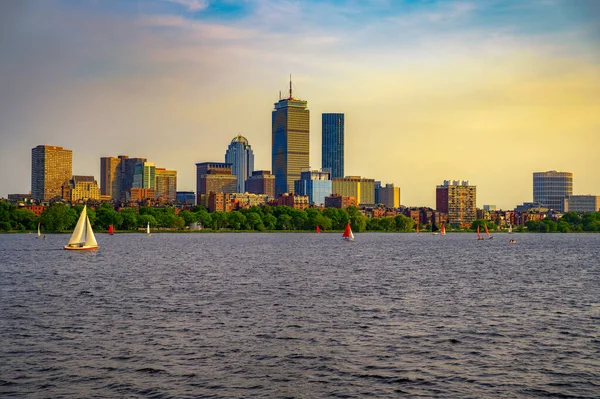 Boston, Massachusetts üzerinde gün batımı manzarası, ikonik Back Bay silueti Charles Nehri 'ni yansıtıyor. Küçük yelkenliler sakin şehir sahnesine hayat katıyor..