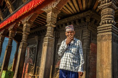 Old buddhist monk smoking cigarette in his temple in Kathmandu