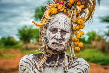 Old woman from the african tribe Mursi in her village