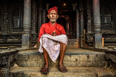 Old buddhist monk sitting in front of his temple in Kathmandu