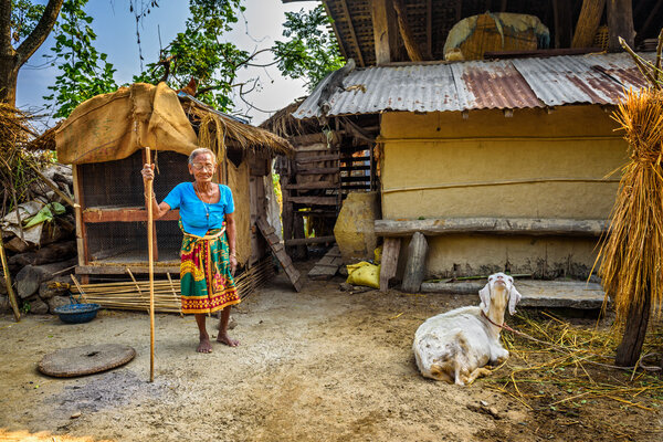 Very old nepalese woman and her goat in the backyard of her house