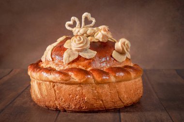 Ekmek masada yatıyor. Düğün pastası koyu bir arka planda yakın plan. Tatil pastası, düğün ekmeği. 