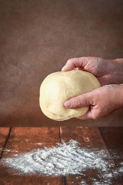 Le mani di una donna anziana e grassoccia impastano la pasta su un tavolo di legno. Preparazione di pasta a una torta festiva, una pizza — Foto Stock