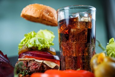 Lezzetli sulu hamburger ve karbonatlı içecek.