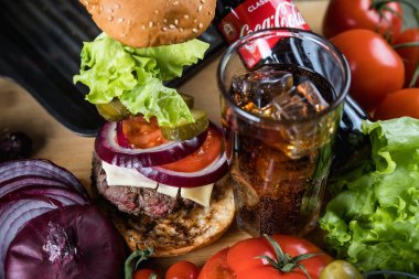 Rusya, Moskova, 18 Ocak 2021. Peynirli hamburger, domates, marul, sos ve bir şişe Coca-Cola..