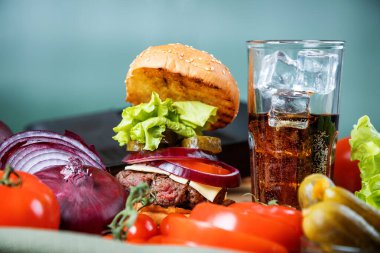 Lezzetli sulu hamburger ve karbonatlı içecek.