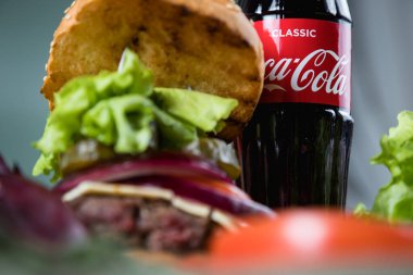 Rusya, Moskova, 15 Ocak 2021. Peynirli hamburger, domates, marul, sos ve bir şişe Coca-Cola..