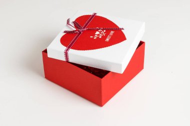 Kırmızı ve beyaz hediyeyi parlak bir arka planda kurdeleyle sar. Hediye kutusu.