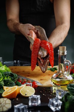 Büyük somon, şefin elinde. Kırmızı havyarı balıktan çıkarmak için bıçak kullanıyor..