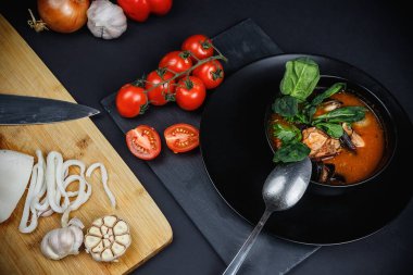 Deniz ürünleri ve sebzeli çorba. Karanlık bir arka planda hayat. Balık suyunda karides ve kalamar..