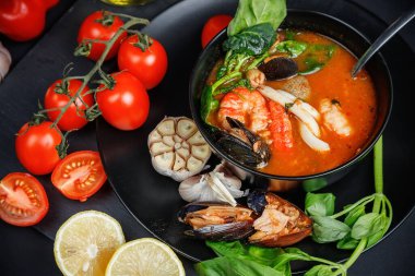 Deniz ürünleri ve sebzeli çorba. Karanlık bir arka planda hayat. Balık suyunda karides ve kalamar..