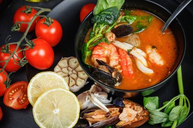 Deniz ürünleri ve sebzeli çorba. Karanlık bir arka planda hayat.