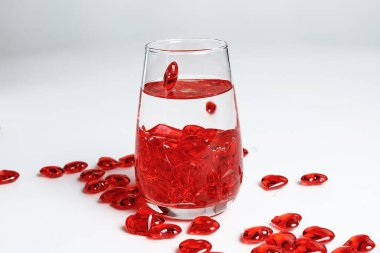 Sevgililer Günü. Bir bardak suda küçük kırmızı cam kalpler. Bir damla sıvı..