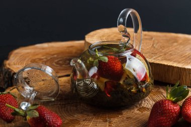 Limonlu ve çilekli sıcak çay. Cam çaydanlık. Tahta tezgah. Sıçrama.