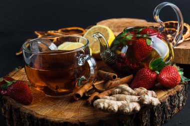 Cam bir fincanda, ahşap bir masada, koyu arkaplanda yabani böğürtlenli meyveli kırmızı çay.