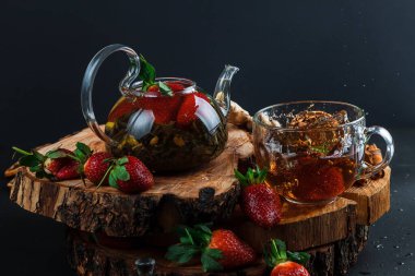 Limonlu ve çilekli sıcak çay. Cam çaydanlık. Tahta tezgah. Sıçrama.