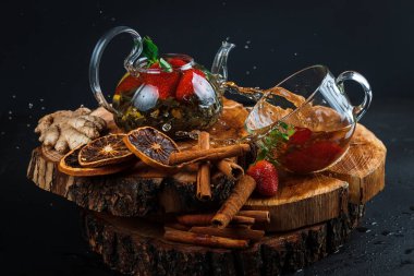 Siyah arka planda cam çaydanlıkta meyveli kırmızı çay.
