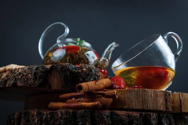 Cam bir fincanda, ahşap bir masada, koyu arkaplanda yabani böğürtlenli meyveli kırmızı çay.