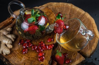 Cam bir fincanda, ahşap bir masada, koyu arkaplanda yabani böğürtlenli meyveli kırmızı çay.