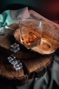 Siyah ahşap masada eski bir viski şişesi. Karanlık arka planda içkiler bulanık.