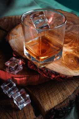 Siyah ahşap masada eski bir viski şişesi. Karanlık arka planda içkiler bulanık.