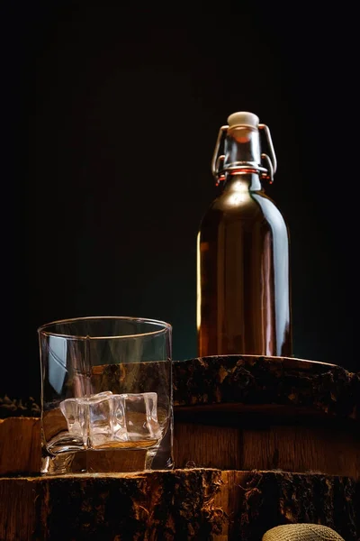 Old whiskey bottle on black wooden table. Drinks on a dark blurred background.