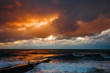 Fırtınadan sonra deniz kıyısında destansı karanlık günbatımı gökyüzü. Dramatik parlak kırmızı bulutlar, doğal doku, arka plan. 