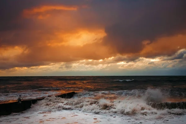 Abstract and colorful storm clouds. Sea sunset. A storm at sea. The waves hit the shore.