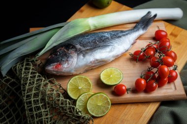 Taze pişmemiş dorado ya da limon dilimleri, baharatlar, şifalı otlar ve sebzeli çipura balığı. Akdeniz mutfağı. 
