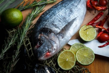 Taze pişmemiş dorado ya da limon dilimleri, baharatlar, şifalı otlar ve sebzeli çipura balığı. Akdeniz mutfağı. 