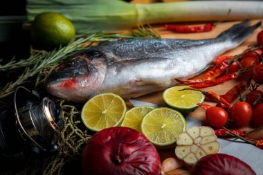 Taze pişmemiş dorado ya da limon dilimleri, baharatlar, şifalı otlar ve sebzeli çipura balığı. Akdeniz mutfağı. 