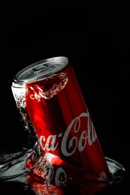 Moskova, Rusya. 6 Nisan 2021. Siyah arka planda kırmızı bir Coca-Cola kutusu. Suya bir kutu soda düşer. Bir damla su..