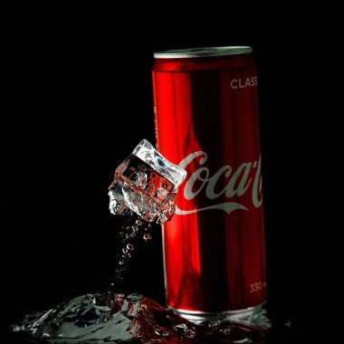 Moskova, Rusya. 6 Nisan 2021. Siyah arka planda kırmızı bir Coca-Cola kutusu. Suya bir kutu soda düşer. Bir damla su..