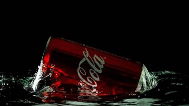 Moskova, Rusya. 6 Nisan 2021. Siyah arka planda kırmızı bir Coca-Cola kutusu. Suya bir kutu soda düşer. Bir damla su..