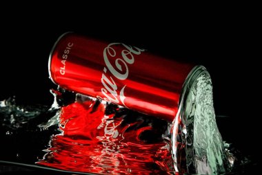 Moskova, Rusya. 6 Nisan 2021. Siyah arka planda kırmızı bir Coca-Cola kutusu. Suya bir kutu soda düşer. Bir damla su..