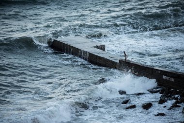 Beton bir iskelede deniz dalgaları kırılır. Dalgakıran. Element. Elementlerin gücü. Akşam denizi.