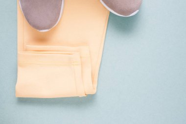 Fotokopi alanı olan mavi bir arka planda spor ayakkabısı ve spor pantolonu. Düz yatış, üst görünüm