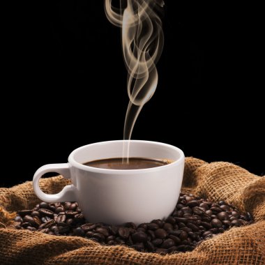 Cup of hot coffee on coffee beans clipart