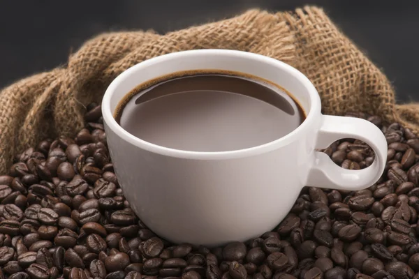 Xícara de café quente em grãos de café — Fotografia de Stock