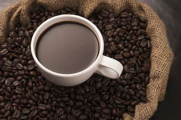 Чашка горячего кофе на кофейных зеренах — стоковое фото