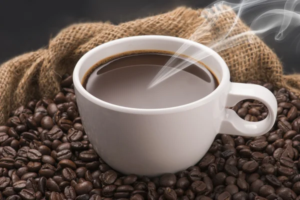 Φλιτζάνι ζεστό καφέ σε κόκκους καφέ — Φωτογραφία Αρχείου