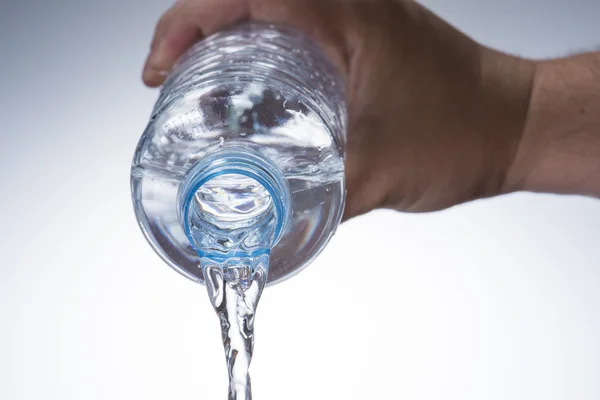 Ręka wlać wodę z butelki z wodą do szkła — Zdjęcie stockowe