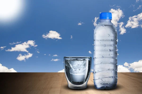 Fles water en ijsblokjes glas — Stockfoto