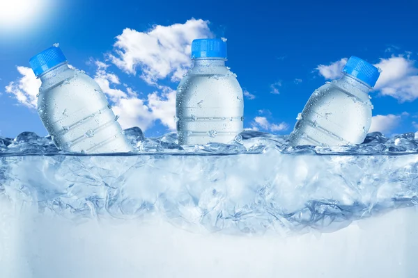 Бутылки холодной воды в кубиках льда — стоковое фото
