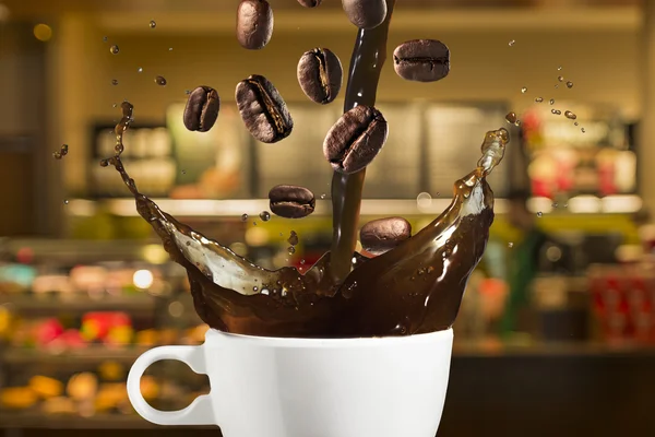 Granos de café cayendo en el café — Foto de Stock