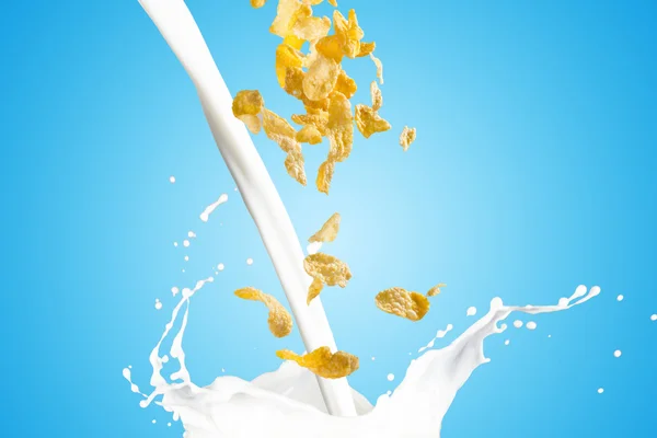 Flocos de milho caindo em respingo de leite — Fotografia de Stock
