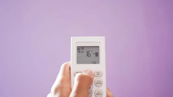 Close up of hand turn on air conditioner with remote control